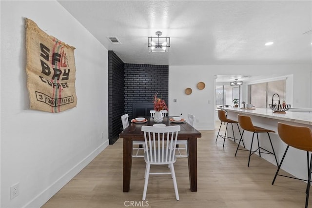 dining room featuring visible vents, baseboards, an inviting chandelier, and light wood finished floors