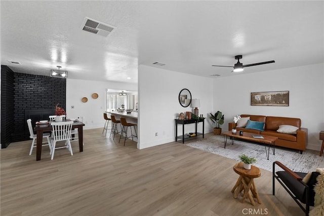 living area with visible vents, a textured ceiling, wood finished floors, and a fireplace