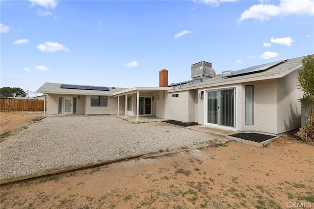 back of house featuring solar panels, fence, stucco siding, cooling unit, and a patio area