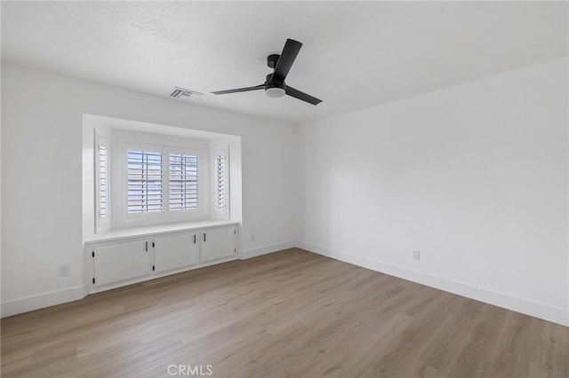 empty room with visible vents, ceiling fan, light wood-type flooring, and baseboards