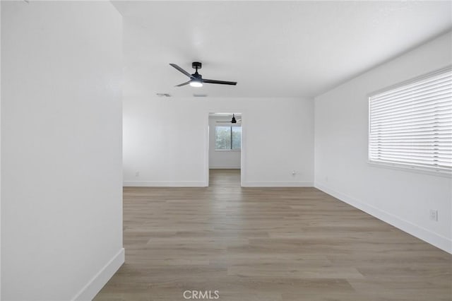 empty room with baseboards, light wood-style flooring, and a ceiling fan