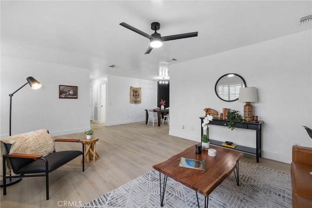 living room with baseboards, light wood-style floors, and a ceiling fan