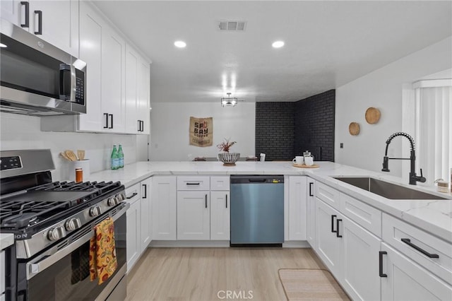 kitchen featuring visible vents, light wood-type flooring, appliances with stainless steel finishes, white cabinetry, and a sink