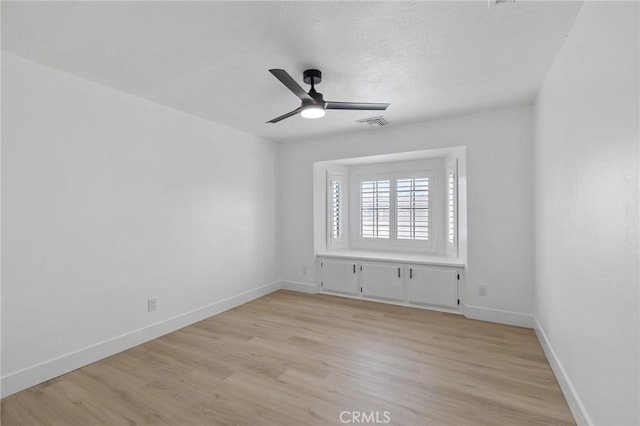 empty room featuring visible vents, baseboards, light wood-type flooring, and ceiling fan