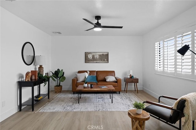 living room featuring visible vents, ceiling fan, baseboards, and wood finished floors