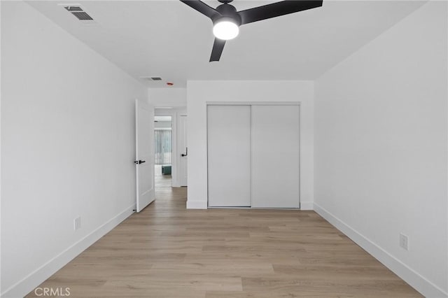 unfurnished bedroom featuring visible vents, a closet, light wood finished floors, baseboards, and ceiling fan