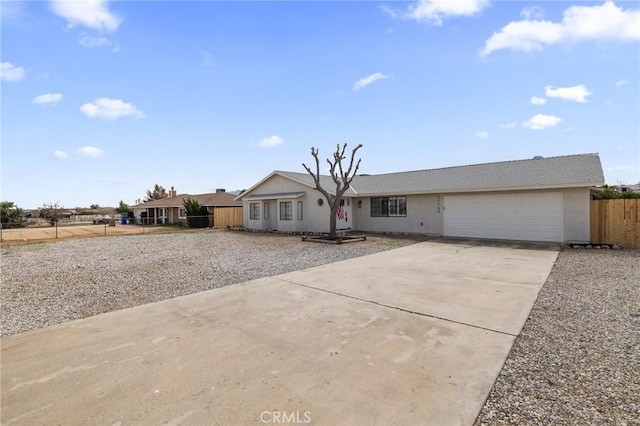 ranch-style house with an attached garage, concrete driveway, and fence