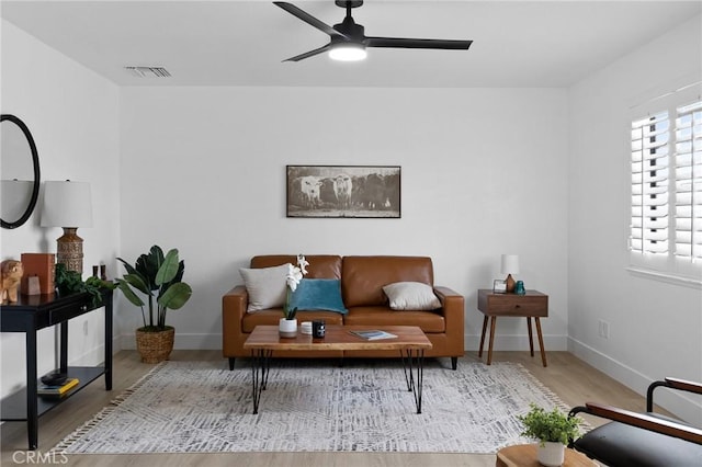 living area with a ceiling fan, wood finished floors, visible vents, and baseboards