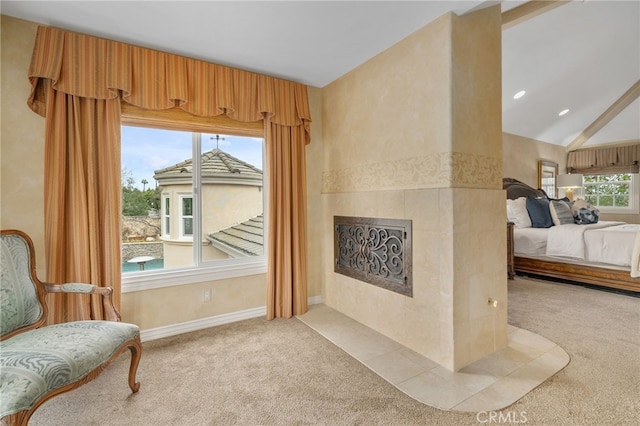 living area featuring a tiled fireplace, vaulted ceiling, light colored carpet, and baseboards