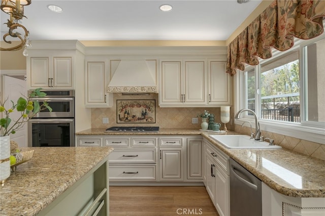 kitchen with premium range hood, a sink, light wood-style floors, appliances with stainless steel finishes, and backsplash