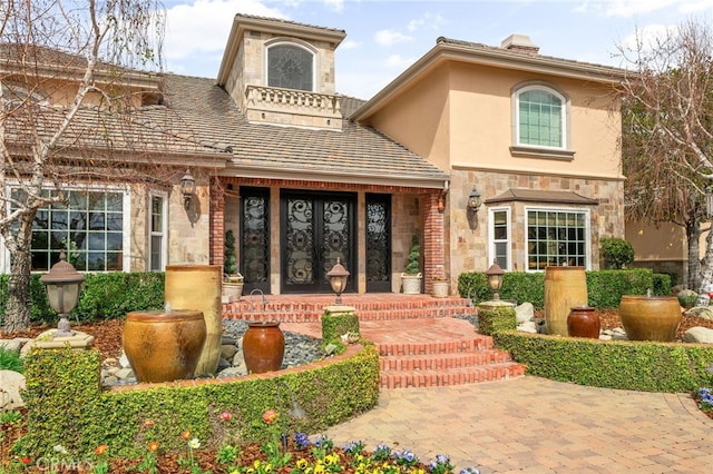 view of exterior entry featuring stone siding and stucco siding