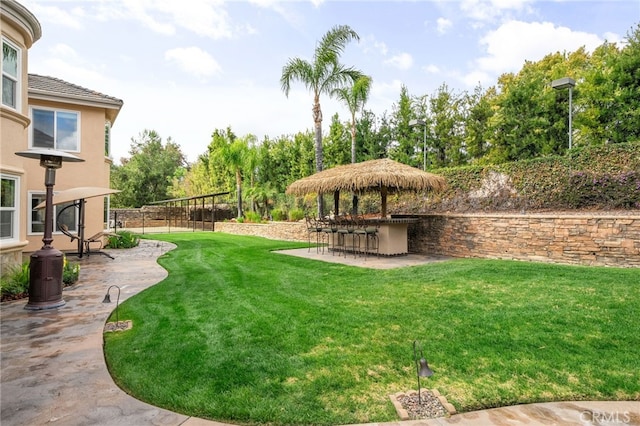 view of yard with a patio, fence, and outdoor dry bar