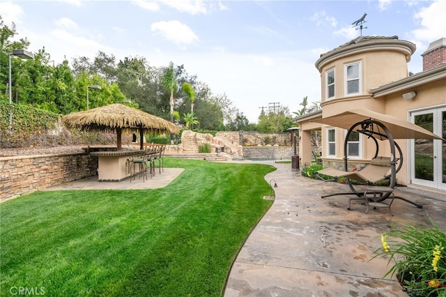 view of yard with outdoor dry bar, french doors, and a patio