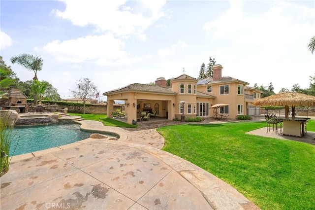 rear view of property with stucco siding, a fireplace, a chimney, a yard, and a patio