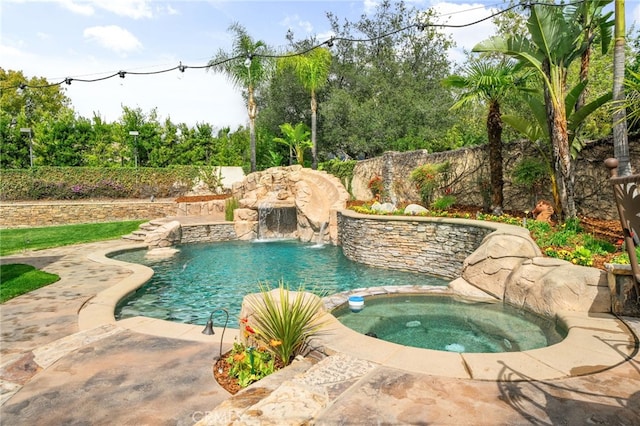 view of pool with fence and a pool with connected hot tub