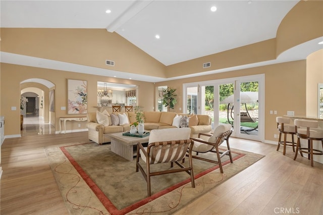 living area featuring light wood finished floors, visible vents, beamed ceiling, arched walkways, and high vaulted ceiling