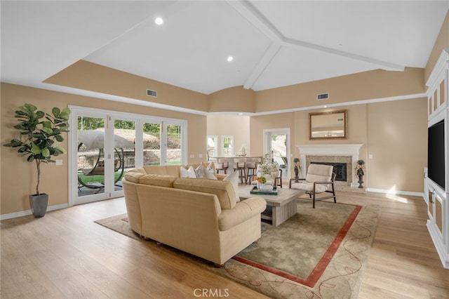 living room with visible vents, plenty of natural light, light wood-style flooring, and a high end fireplace