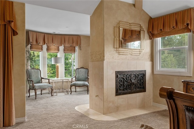 sitting room featuring a wealth of natural light, a tiled fireplace, and carpet floors