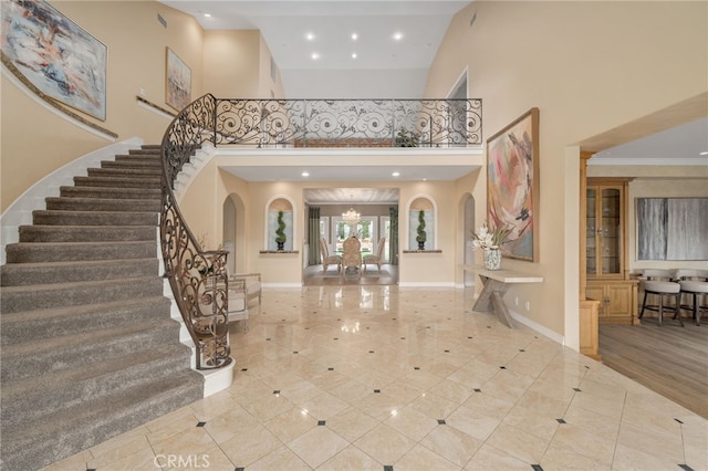 entryway with stairway, baseboards, arched walkways, and a towering ceiling