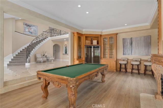 game room featuring arched walkways, light wood-style flooring, billiards, and ornamental molding