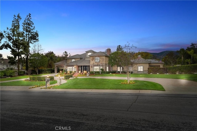 french provincial home with a lawn, curved driveway, and a chimney