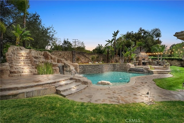 view of swimming pool featuring an outdoor stone fireplace and a patio area