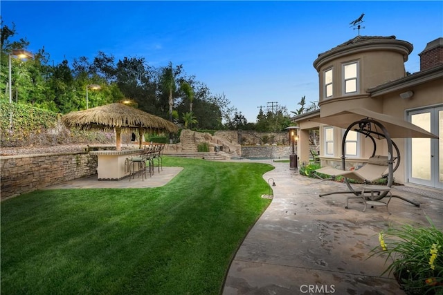 view of yard with french doors, outdoor dry bar, and a patio area