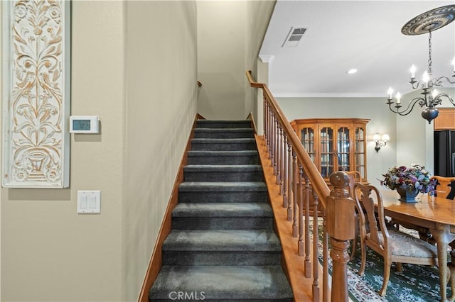 stairs featuring visible vents, an inviting chandelier, and crown molding