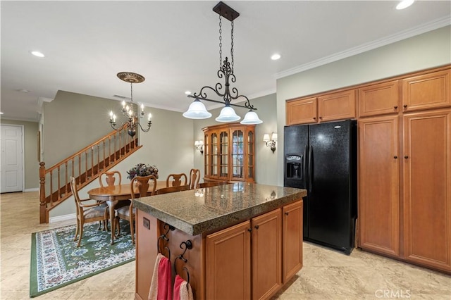 kitchen featuring brown cabinetry, a kitchen island, hanging light fixtures, crown molding, and black refrigerator with ice dispenser