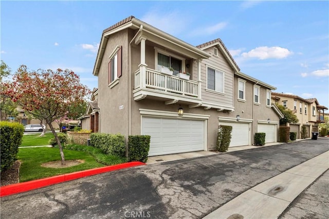 multi unit property with a balcony, a garage, a residential view, and stucco siding