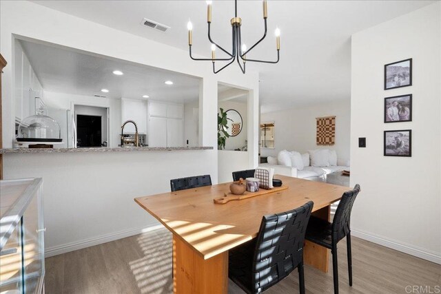 dining space with wood finished floors, baseboards, visible vents, recessed lighting, and a chandelier