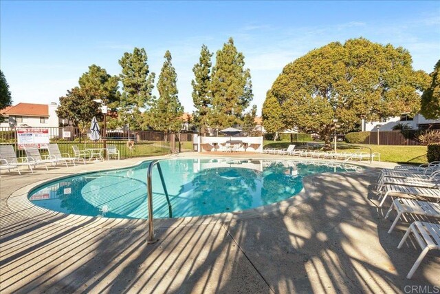 community pool with a patio and fence