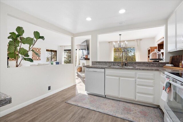 kitchen featuring light wood-style flooring, a sink, white cabinetry, white appliances, and an inviting chandelier