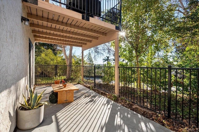 view of patio with a balcony and fence