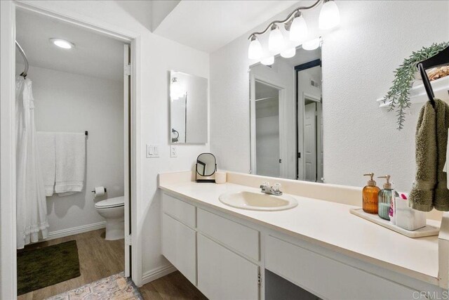 bathroom featuring vanity, a shower with curtain, wood finished floors, baseboards, and toilet