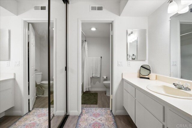 bathroom with visible vents, toilet, wood finished floors, and vanity