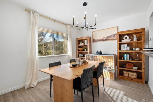 dining area featuring baseboards, an inviting chandelier, and wood finished floors