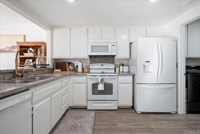 kitchen featuring white appliances, washer / clothes dryer, a sink, white cabinetry, and light wood-type flooring