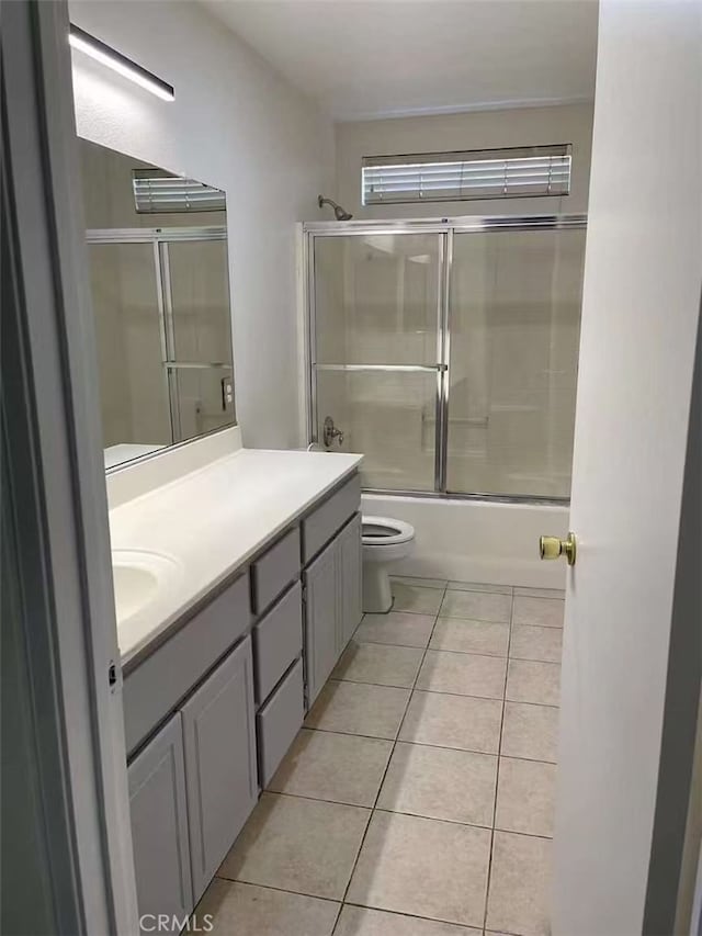 full bathroom with tile patterned floors, shower / bath combination with glass door, vanity, and toilet