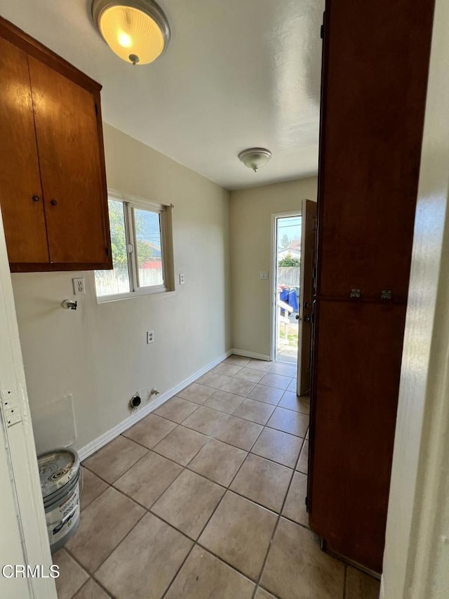 laundry area featuring light tile patterned floors, baseboards, cabinet space, and a healthy amount of sunlight