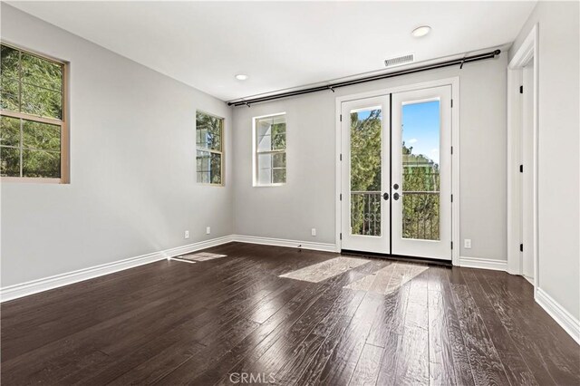 empty room featuring visible vents, french doors, baseboards, and wood-type flooring