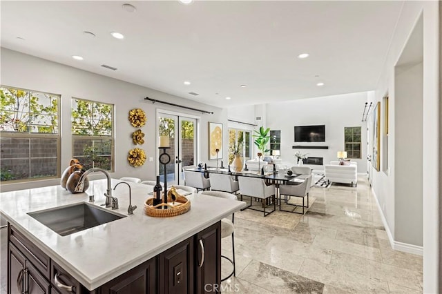 kitchen featuring visible vents, a sink, open floor plan, recessed lighting, and dark brown cabinetry