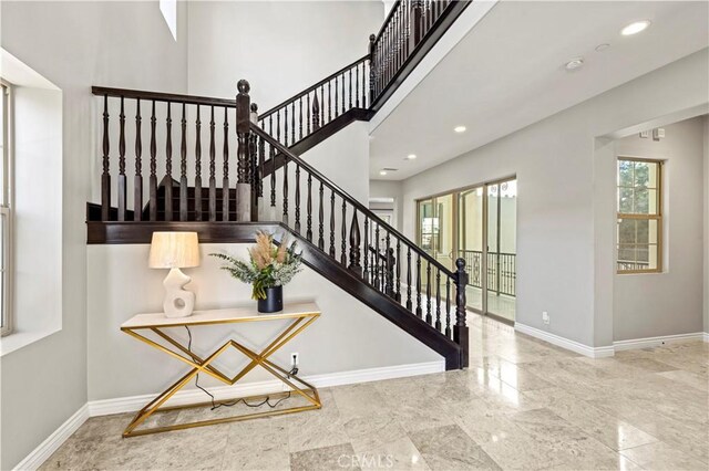 staircase featuring recessed lighting, baseboards, and a high ceiling