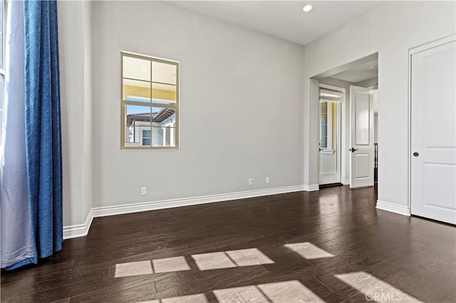 unfurnished room with dark wood-type flooring, recessed lighting, and baseboards