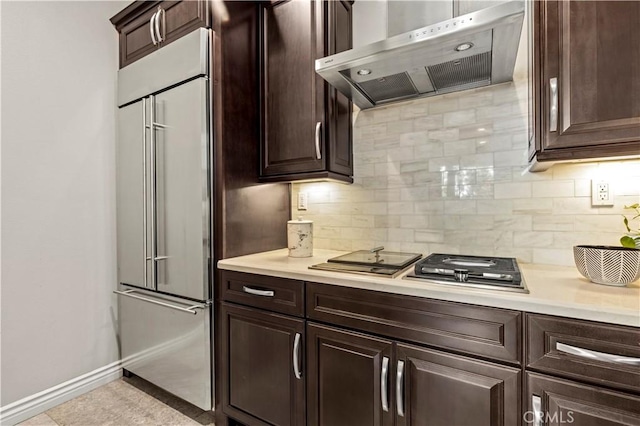 kitchen with dark brown cabinetry, ventilation hood, light countertops, and built in refrigerator