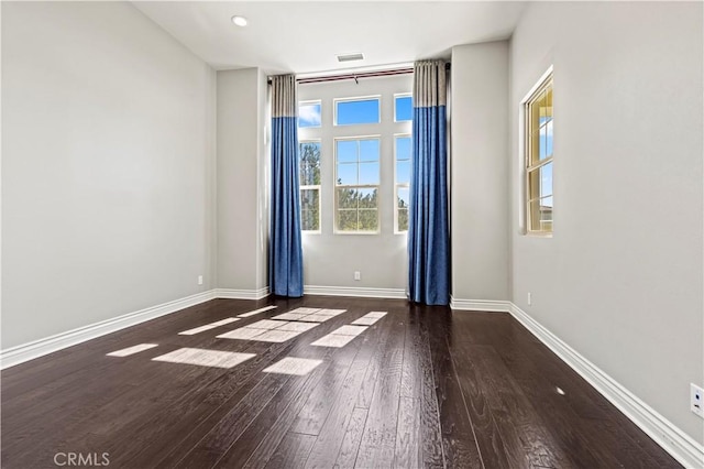 empty room featuring visible vents, wood finished floors, and baseboards