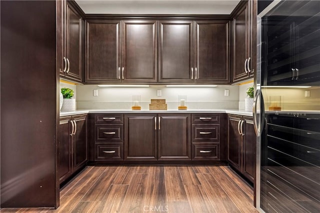 kitchen with light countertops, refrigerator, dark wood-style floors, and dark brown cabinetry