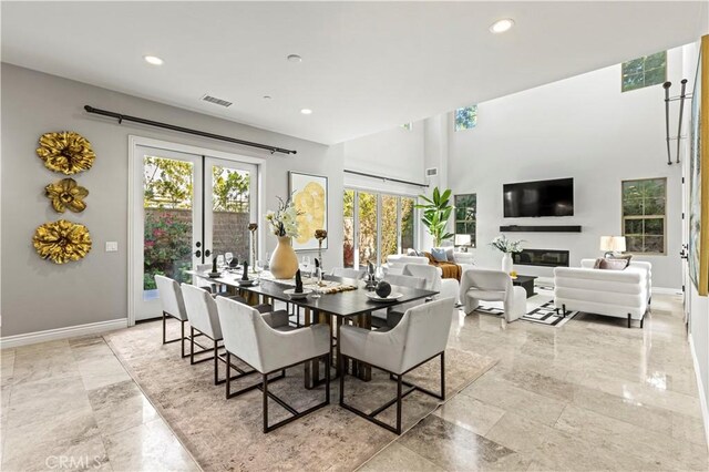 dining area featuring french doors, baseboards, visible vents, and a glass covered fireplace