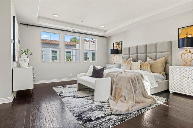 bedroom featuring recessed lighting, a tray ceiling, baseboards, and hardwood / wood-style flooring