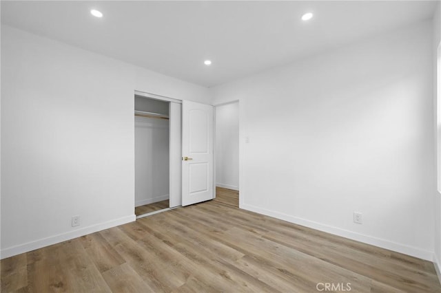 unfurnished bedroom featuring recessed lighting, wood finished floors, baseboards, and a closet